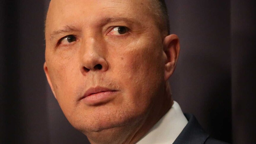 Peter Dutton wearing a dark suit, his eyes darting to the right of frame.