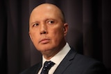 Dutton is wearing a dark suit, his eyes darting to the right of frame.