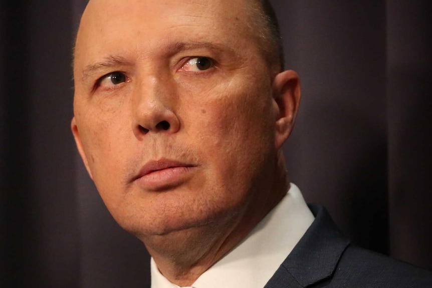 Peter Dutton wearing a dark suit, his eyes darting to the right of frame.