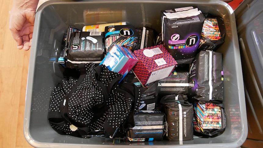 A grey box containing packs of pads and tampons.