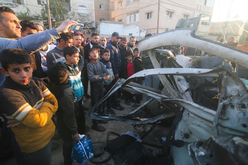 Palestinians gather around a Hamas police vehicle after it was struck by an Israeli airstrike. 