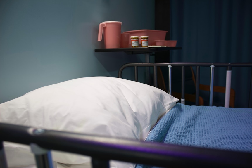 An empty hospital bed with medications beside it.
