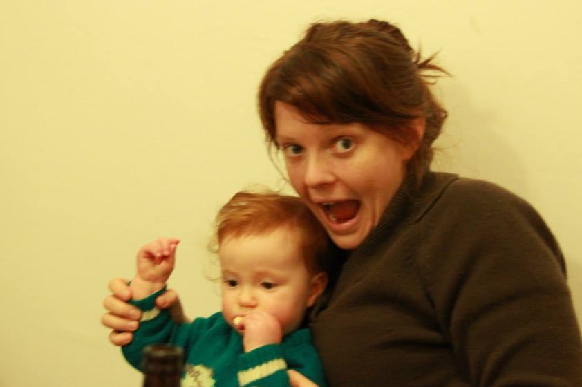 Slightly blurred photo of woman with open-mouthed happy gape, holding a small child on her lap.