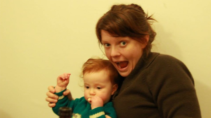 Slightly blurred photo of woman with open-mouthed happy gape, holding a small child on her lap.