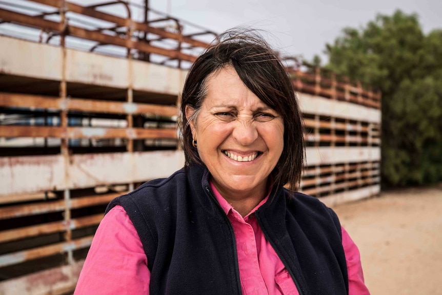 A woman standing in front of a steel carriage used for transporting livestock