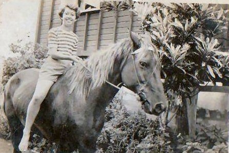 Black-and-white photo of a 13 year-old Esther with short, cropped hair, on the back of a horse