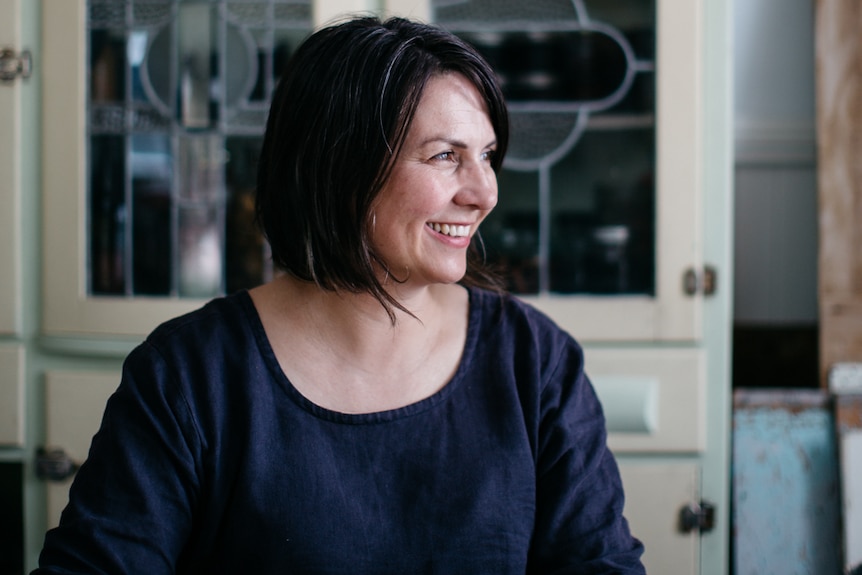 Michelle Crawford podding peas in a kitchen, with a vintage cupboard in background.