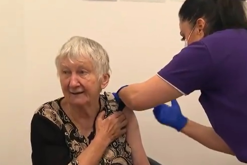 An elderly woman receives a jab.
