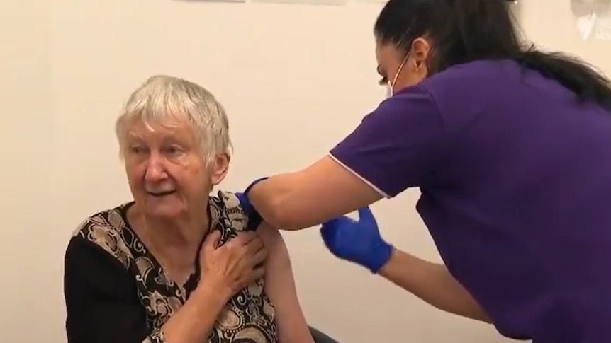 An elderly woman receives a jab.