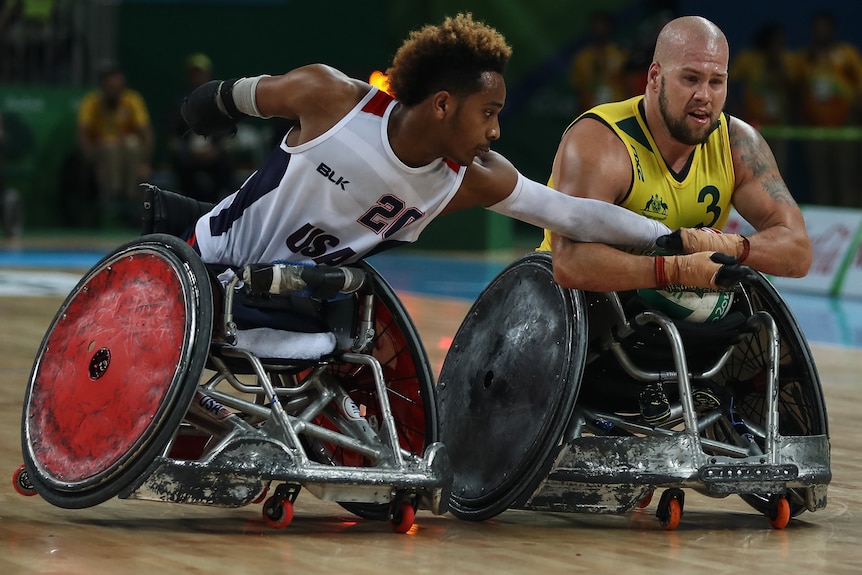An American wheelchair rugby player tries to take the ball off Austrlaia's Ryley Batt.
