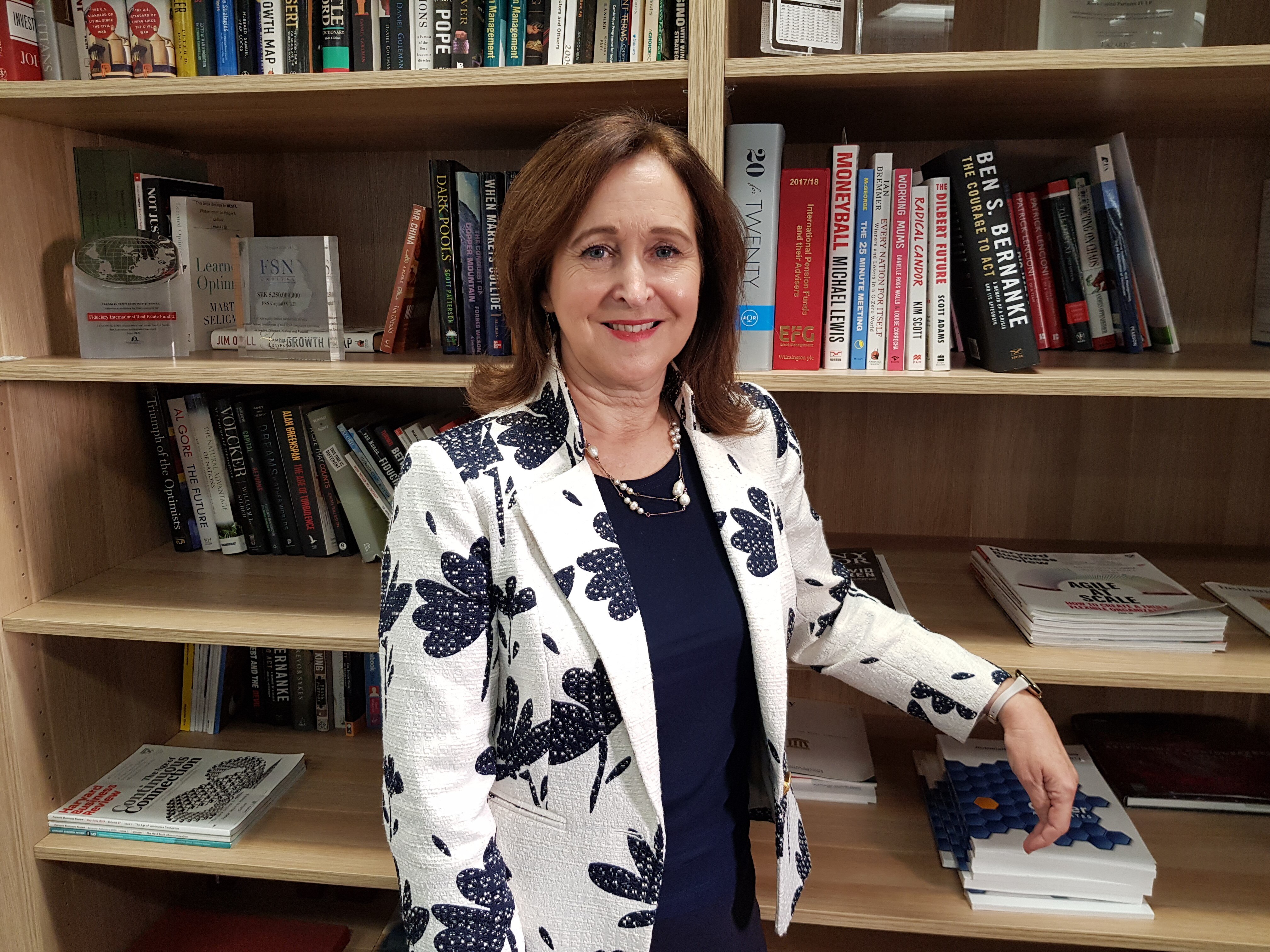 Debby Blakey stands in front of a bookshelf in the library at HESTA's Melbourne office in May 2021. 