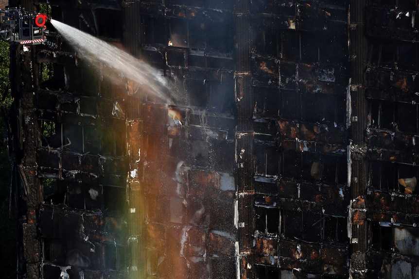 Sun creates a rainbow effect as firefighters work at the scene of  a deadly blaze at a high rise apartment block in London.