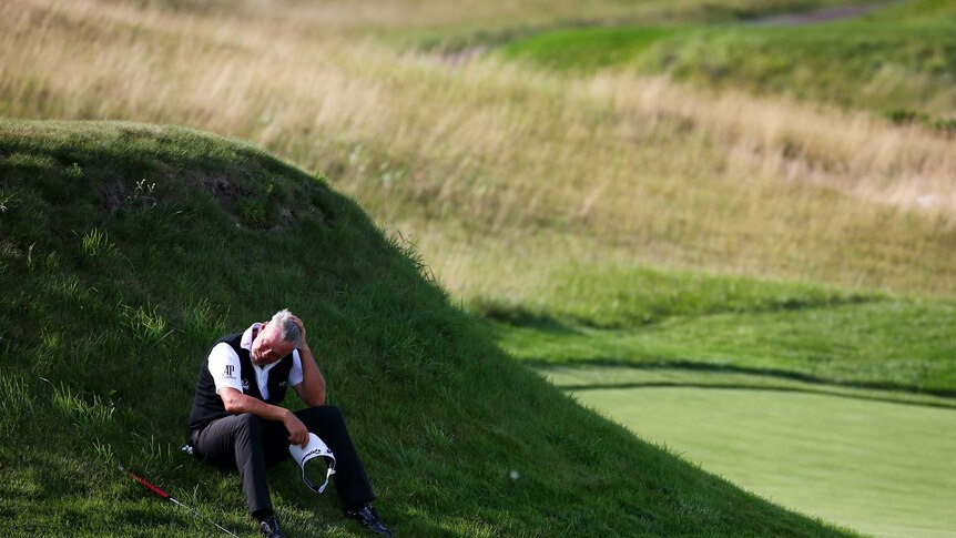 Tough day ... Darren Clarke sits in the grass on the 17th hole during his opening round of 6-over 78