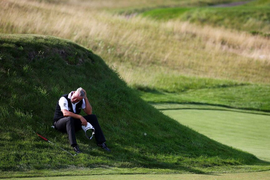 Tough day ... Darren Clarke sits in the grass on the 17th hole during his opening round of 6-over 78