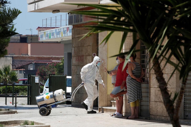 A healthcare worker wearing a protective suit carries an oxygen tank into a residential complex.