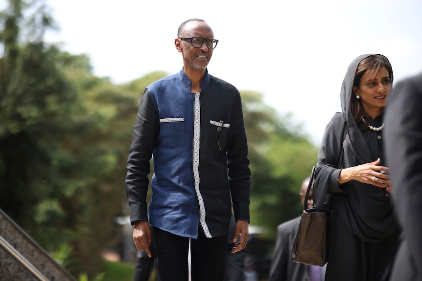 A man and woman wearing traditional attire walk outside