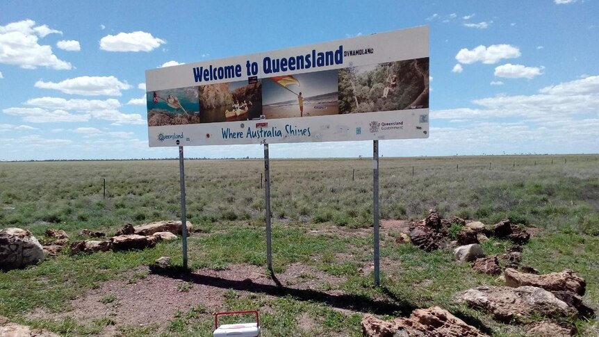 A photo of the red esky in front of a 'Welcome to Queensland' sign at the state's border.