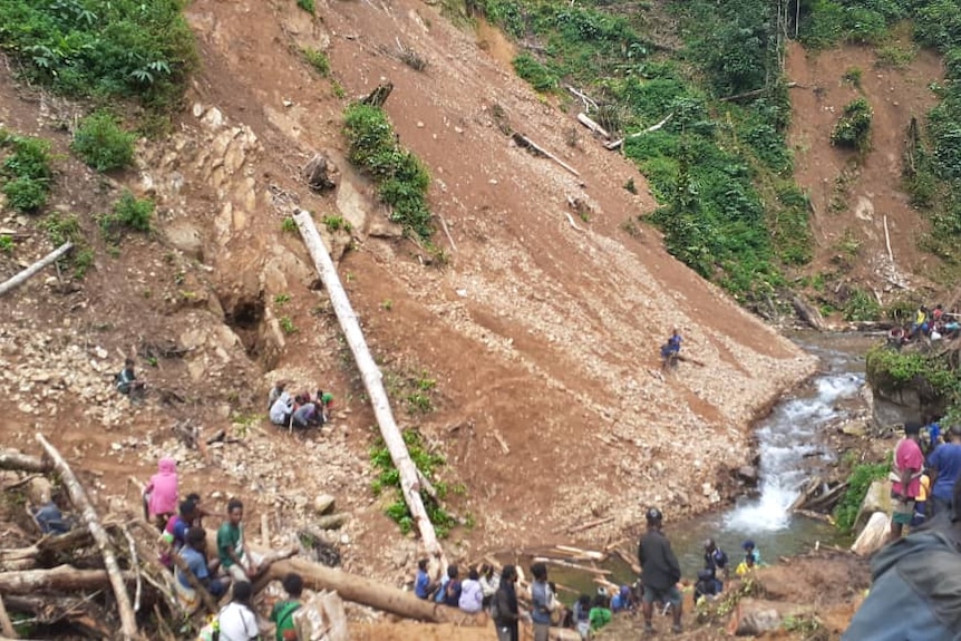 People scattered around at the site of a landslide in PNG.