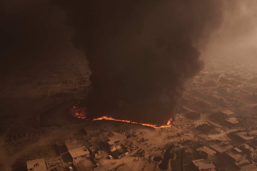 An aerial shot of smoke and fire from a burning oil field.
