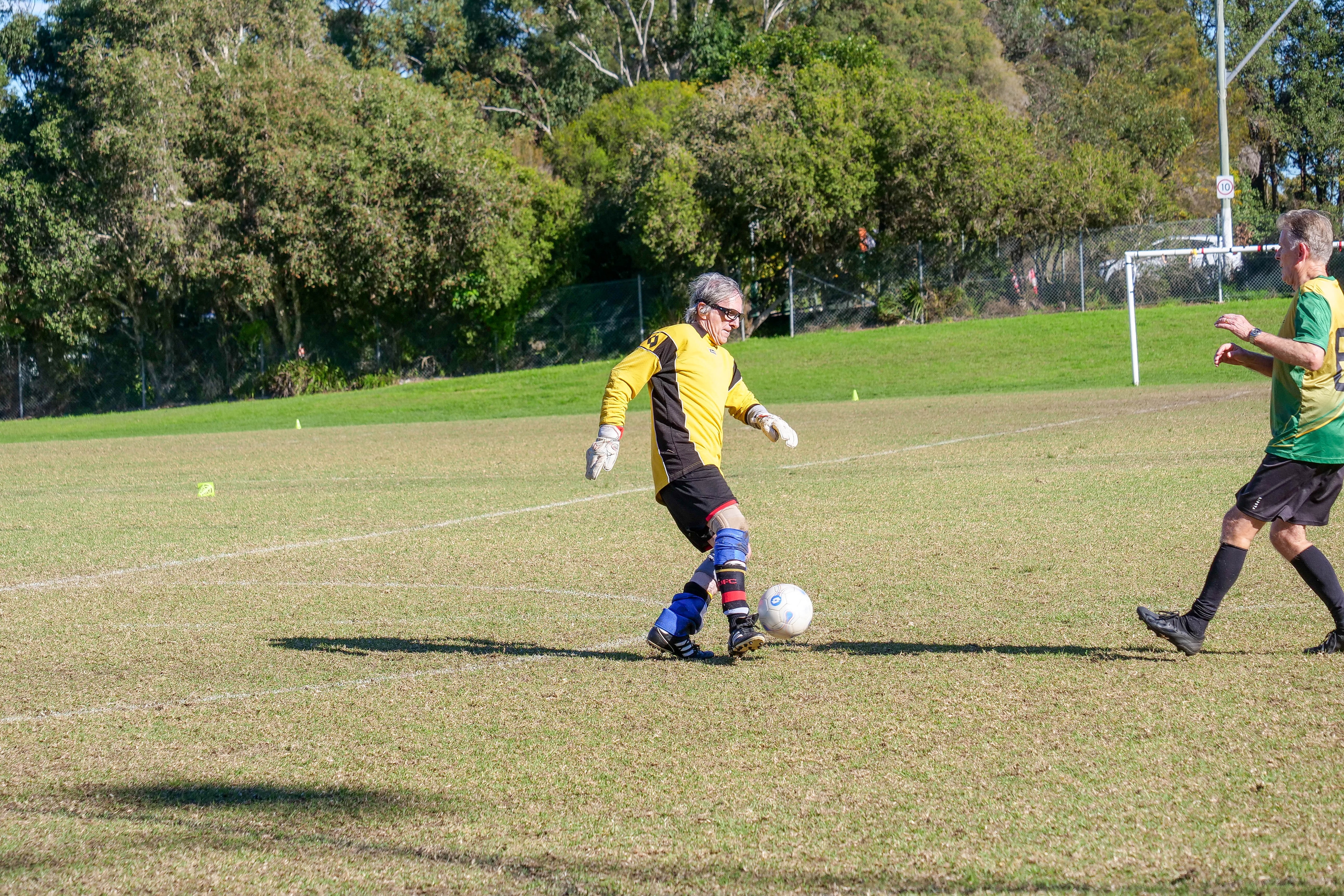 a male goalkeeper dribbles a football at his feet