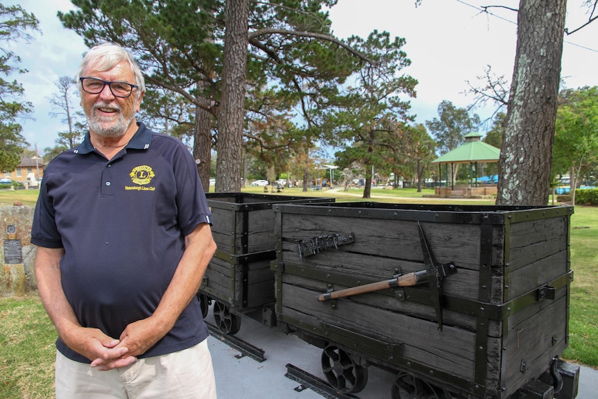 A man stands in front of refurbished wooden skips. 