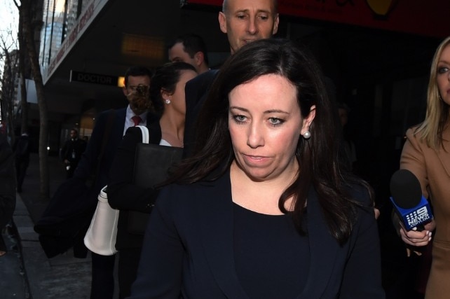 A woman with dark hair walks down a street.