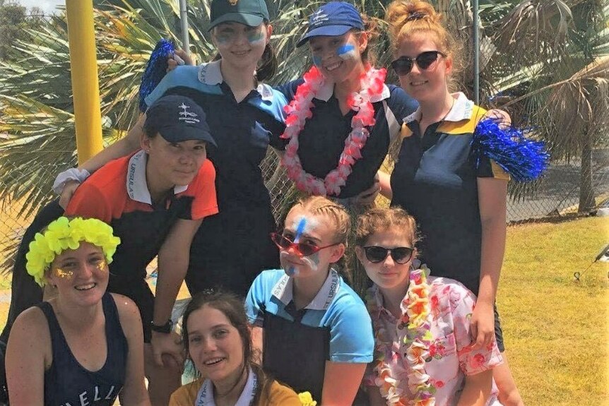 High school girls dressed up for their swimming carnival in polo shirts with painted faces and other accessories.