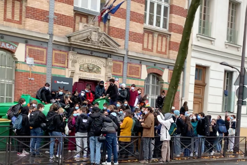 Students huddle in a group to block the front entrance of a school in Paris.