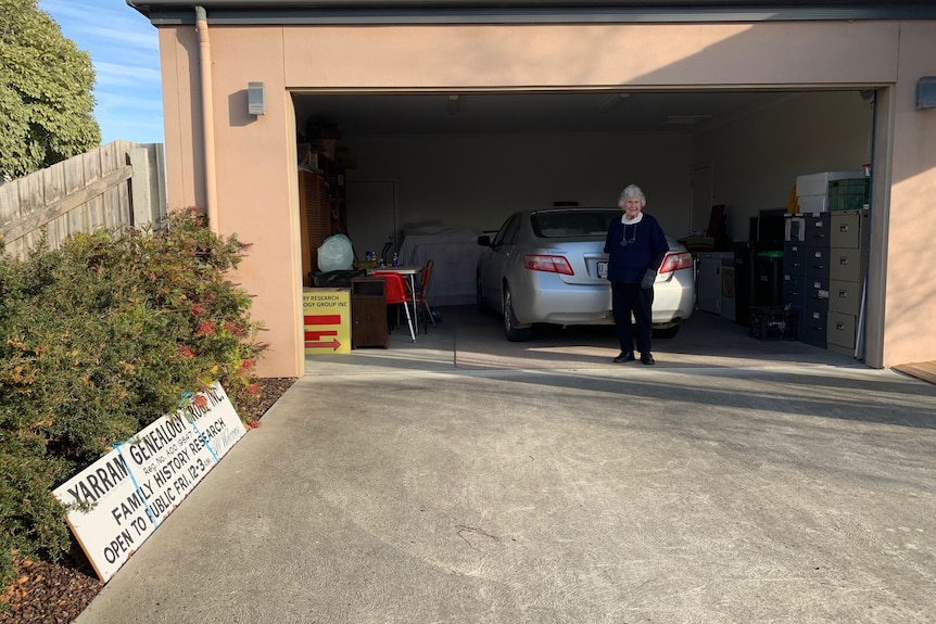 older women stands  in garage with filing cabinets. 