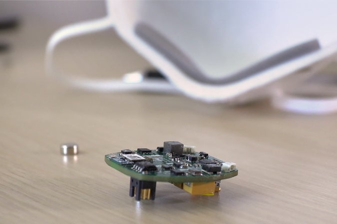 A coin-sized circuit board with several electronic components