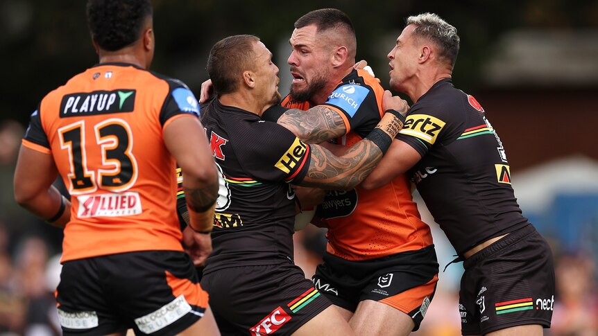NRL player David Klemmer has the ball, and is tackled by two opponents around the body