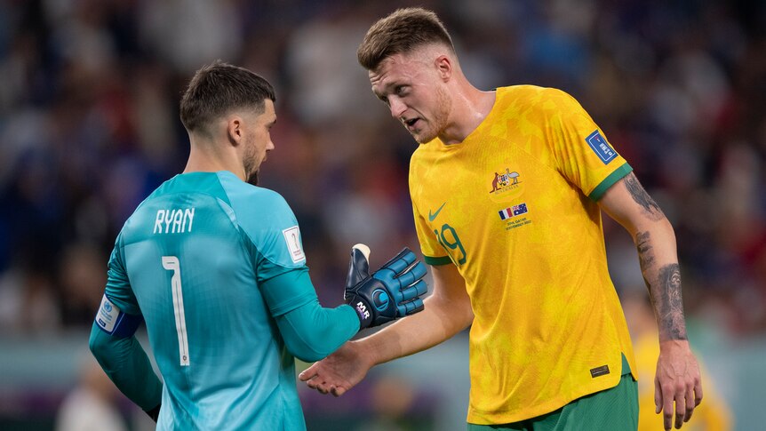 Two Socceroos players speak to each other during the World Cup match against France.