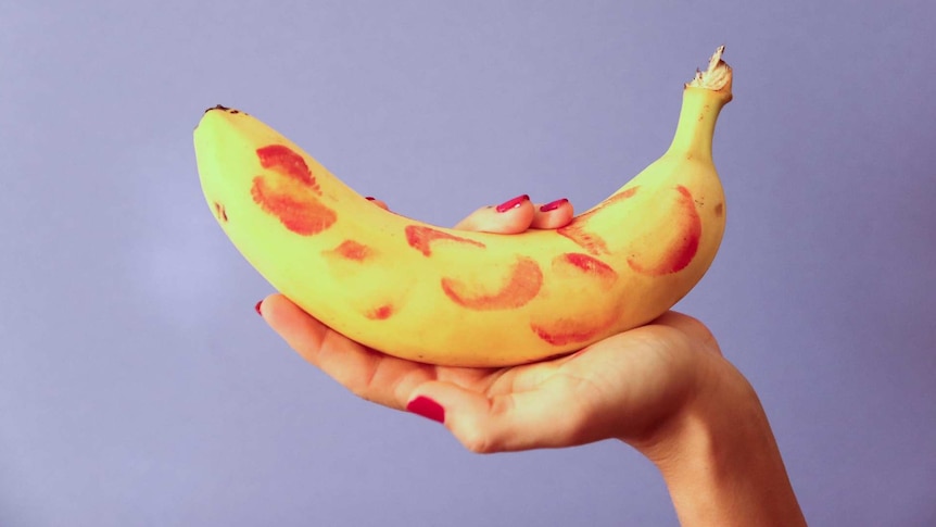 A hand holding a banana with kisses on it
