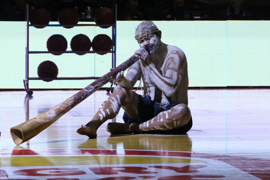 An indigenous man plays the traditional digeridoo ahead of the Hawks game with the Sydney Kings