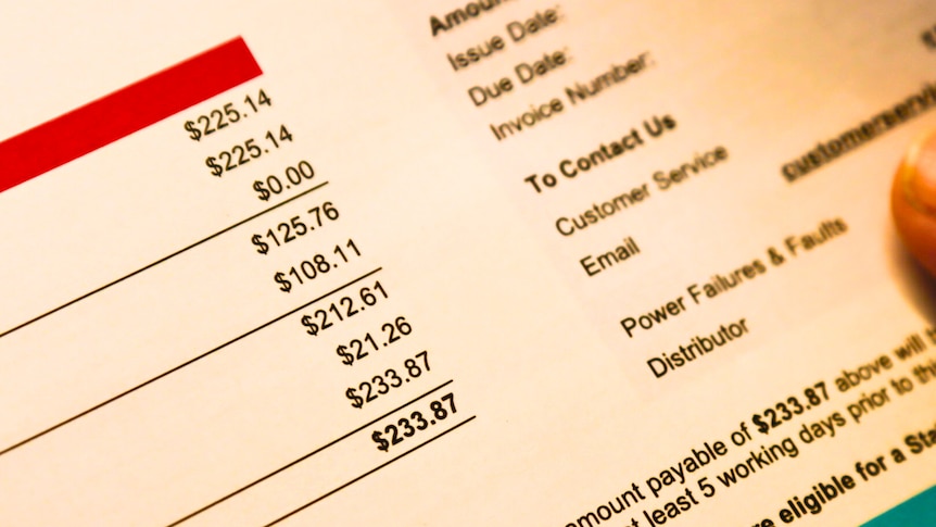 a close-up of a person holding several pages of a household power bill in their hands