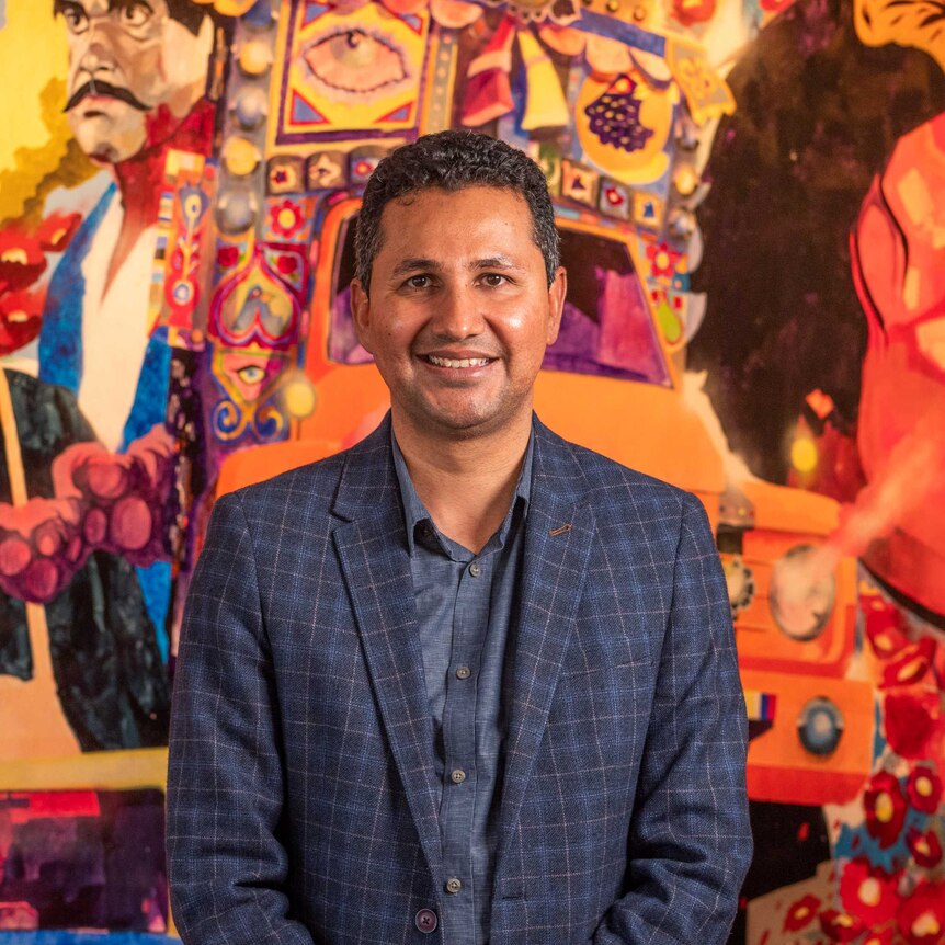 Syed Naqvi - Community Spirit Award nominee standing in front of a bright painted wall