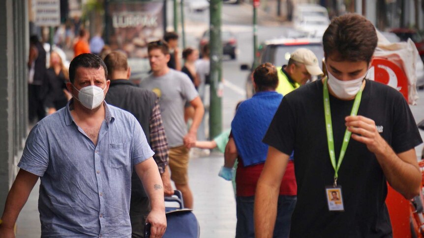 People walking along a Sydney street wearing masks.