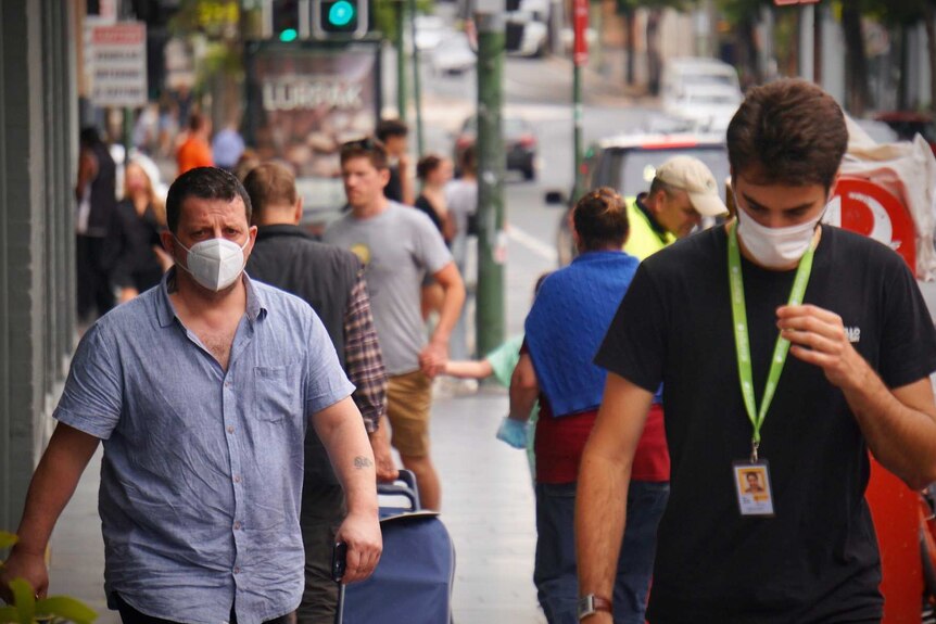 People walking along a Sydney street wearing masks.
