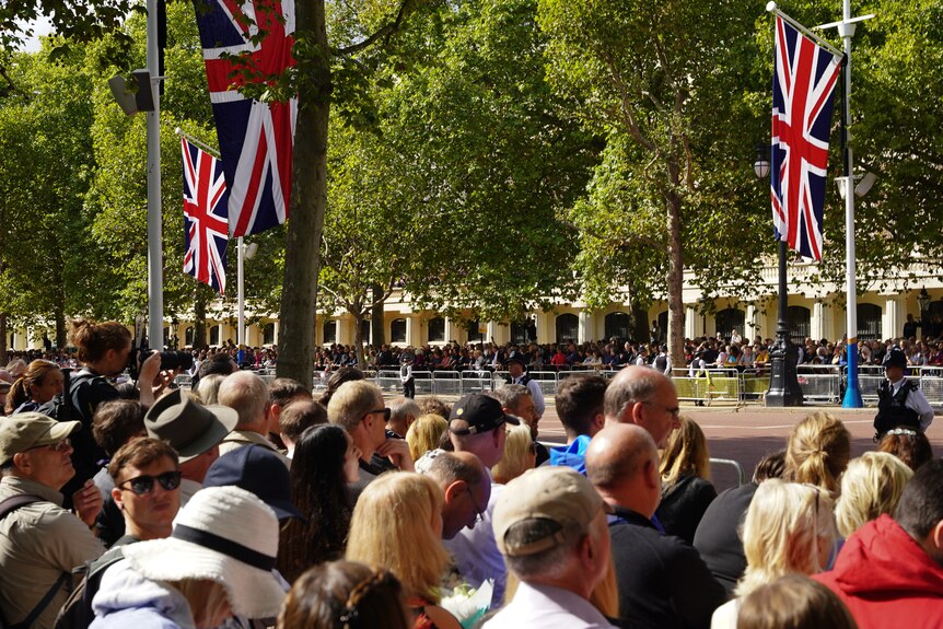 In high sun, the red bitumen of The Mall, Union Jack flags and the crowd can be seen. 