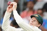 Australia fielder Steve Smith pulls an awkward face as a cricket ball pops out of his hands during a Test against India.