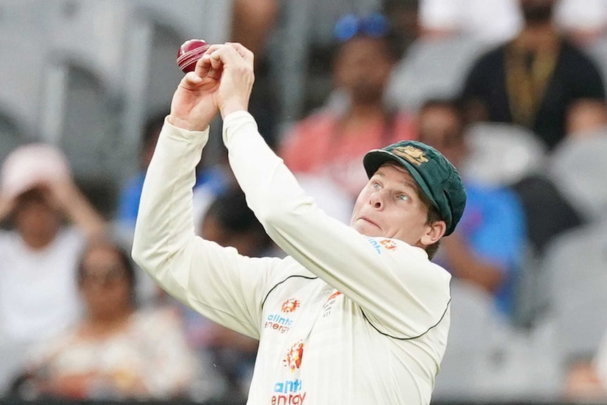 Australia fielder Steve Smith pulls an awkward face as a cricket ball pops out of his hands during a Test against India.