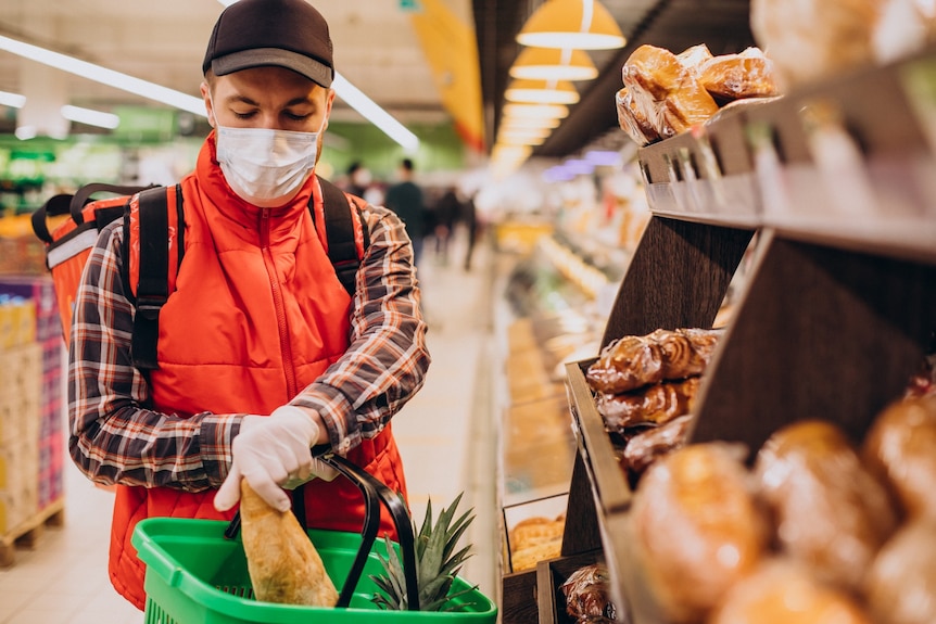 A man wearing a mask buying products at a supermarket