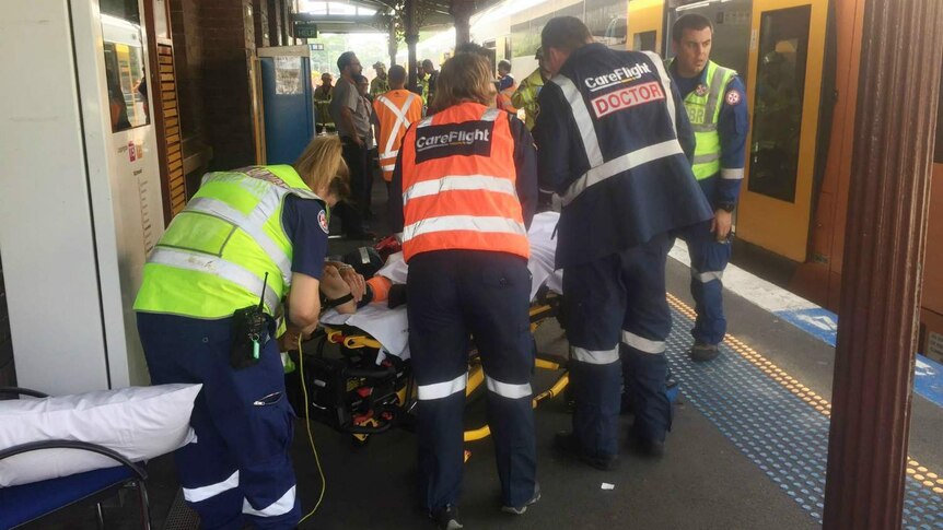 People being taken off a train and put on stretchers.