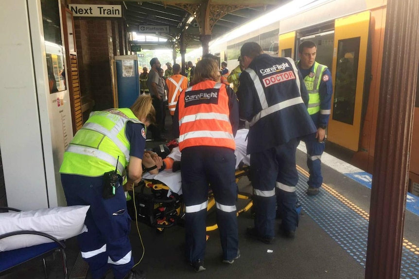 People being taken off a train and put on stretchers.