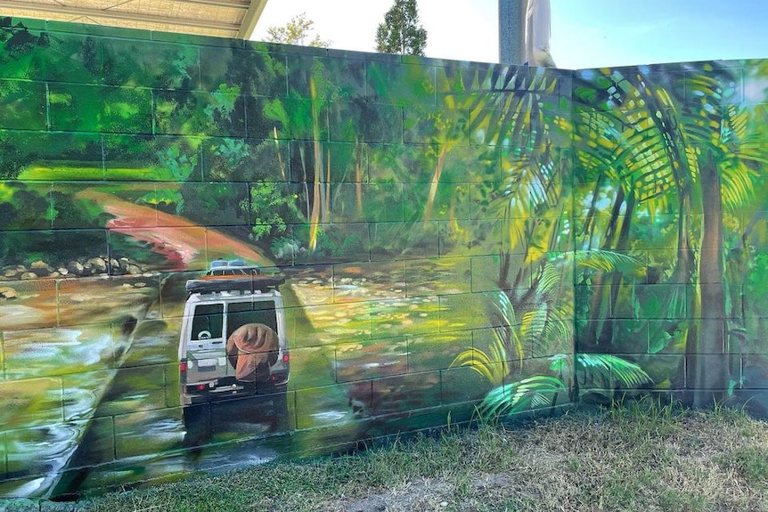 A green mural that depicts a four wheel drive, driving through a rainforest
