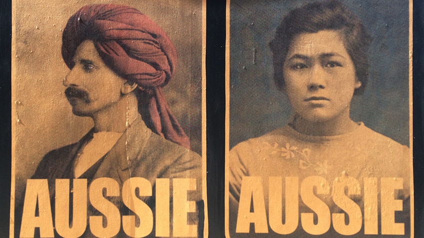 On a black wall, you see two posters showing archival portraits of Asian-Australians, with the word 'Aussie' beneath them.