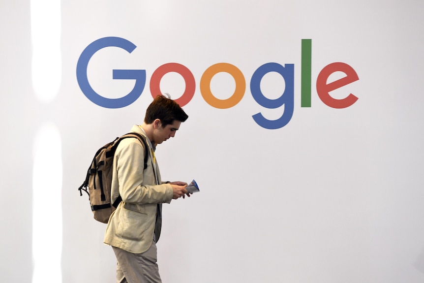 一名男子路过一个拼写为 Google 的彩色徽标