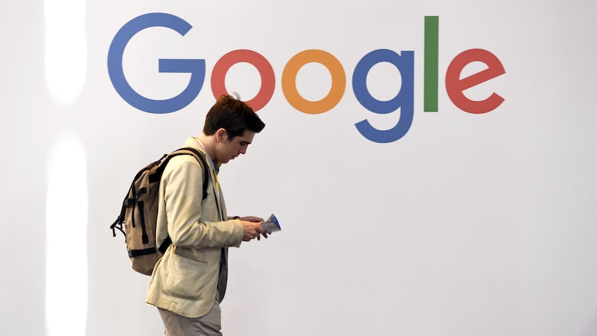 A man walks past a multi-coloured logo spelling Google