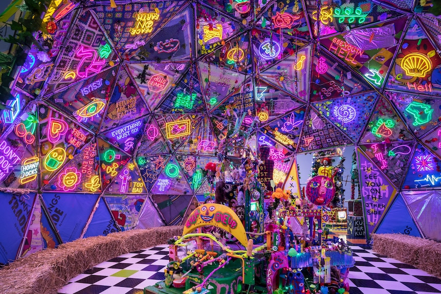 Interior view of a dome-shaped installation decorated with neon lights and a black and white checkered floor