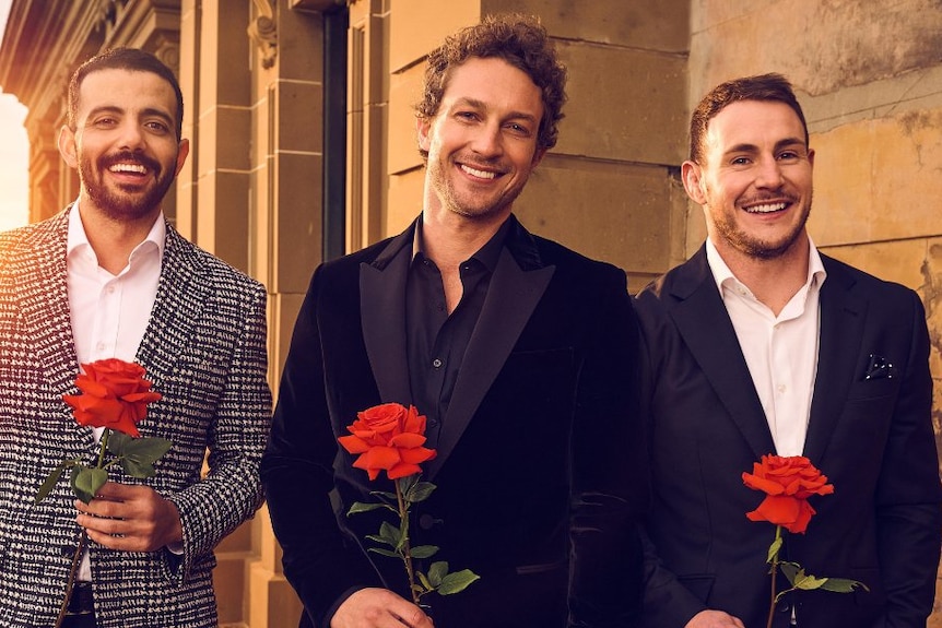 2023 The Bachelors' three suitors stand side-by-side in suits with roses.